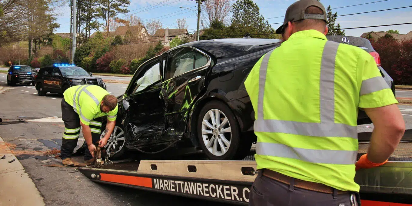 Workers loading wrecked vehicle on tow truck